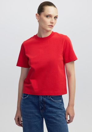 T-shirt rossa in cotone con scollo rotondo classico e maniche corte, con una vestibilità comoda e una texture liscia. Abbinata a jeans in denim blu.