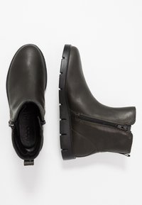 Bottines vert olive foncé en cuir lisse, avec des fermetures éclair latérales, un bout rond et une semelle en caoutchouc noir texturée.