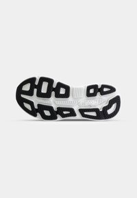 Semelle de chaussure de sport avec un motif distinct en caoutchouc noir et des accents blancs, conçue pour l'adhérence et la stabilité, mettant en avant des surfaces texturées.