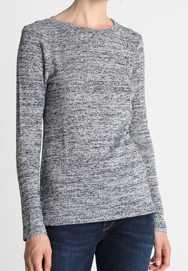 Šedý pletený top s dlouhým rukávem a texturovaným vzorem. Kulatý výstřih a přiléhavé rukávy, kombinované s tmavými džíny. Měkká, pohodlná tkanina.