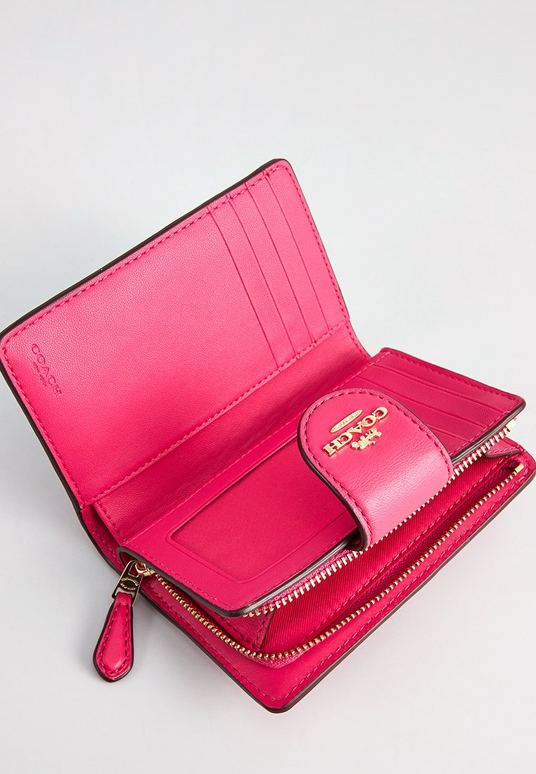 Różowy skórzany portfel z wieloma kieszeniami na karty, zamykaną przegrodą i markowym zapięciem. Gładka tekstura, kompaktowy prostokątny kształt.