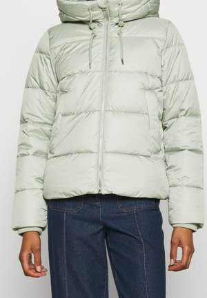 Lichtgroen donzen jack met ritssluiting aan de voorkant, capuchon met trekkoorden, gedragen met donkerblauwe spijkerbroek.