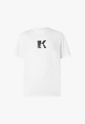 T-shirt bianca in cotone con stampa grafica nera con la lettera "K" e un design a silhouette sul petto. Maniche corte, vestibilità rilassata.