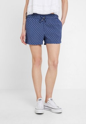 Shorts à fleurs blancs sur fond bleu marine, avec taille à cordon de serrage. Fabriqués en tissu léger, idéaux pour un style décontracté.