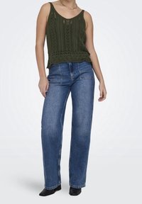 Olive green, knitted tank top with a lace texture and scalloped hem, paired with high-waisted, wide-leg blue denim jeans and black ankle boots.