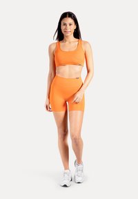 Oranges Sport-BH- und Shorts-Set mit hoher Taille aus elastischem Stoff; zeichnet sich durch eine glatte Textur und minimale Verzierungen aus.
