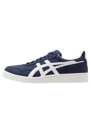 Baskets basses bleu marine avec semelle blanche et bandes blanches croisées sur le côté, avec signature ASICS au talon et à la semelle.