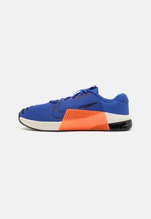 Chaussure de sport en mesh bleu avec une semelle intermédiaire orange uni et une semelle extérieure en caoutchouc noir. Design à lacets avec des accents texturés.