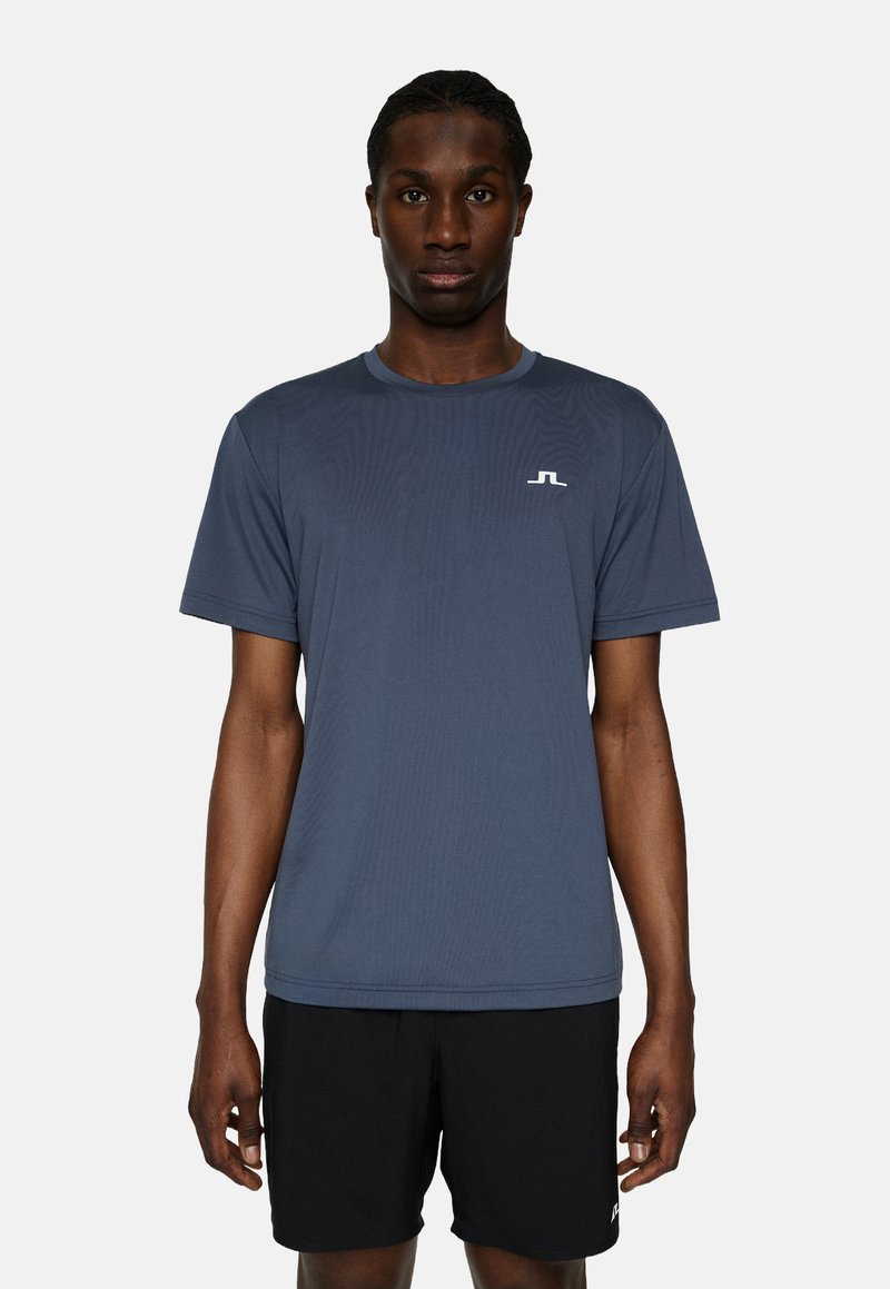 Mans kortärmad träningsskjorta i mörkblått tyg, med rund halsringning och en liten vit logotyp på bröstet.