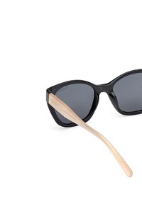 Černé sluneční brýle ve tvaru kočičích očí s tmavými skly a krémovými, štíhlými stranami. Rám má lesklý povrch a geometrický design.