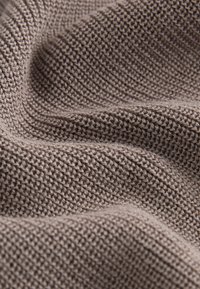 Strukturiertes Gewebe in einem gedämpften Taupe-Farbton mit einem gerippten Strickmuster. Das Gewebe ist gleichmäßig mit einem weichen, flexiblen Erscheinungsbild.