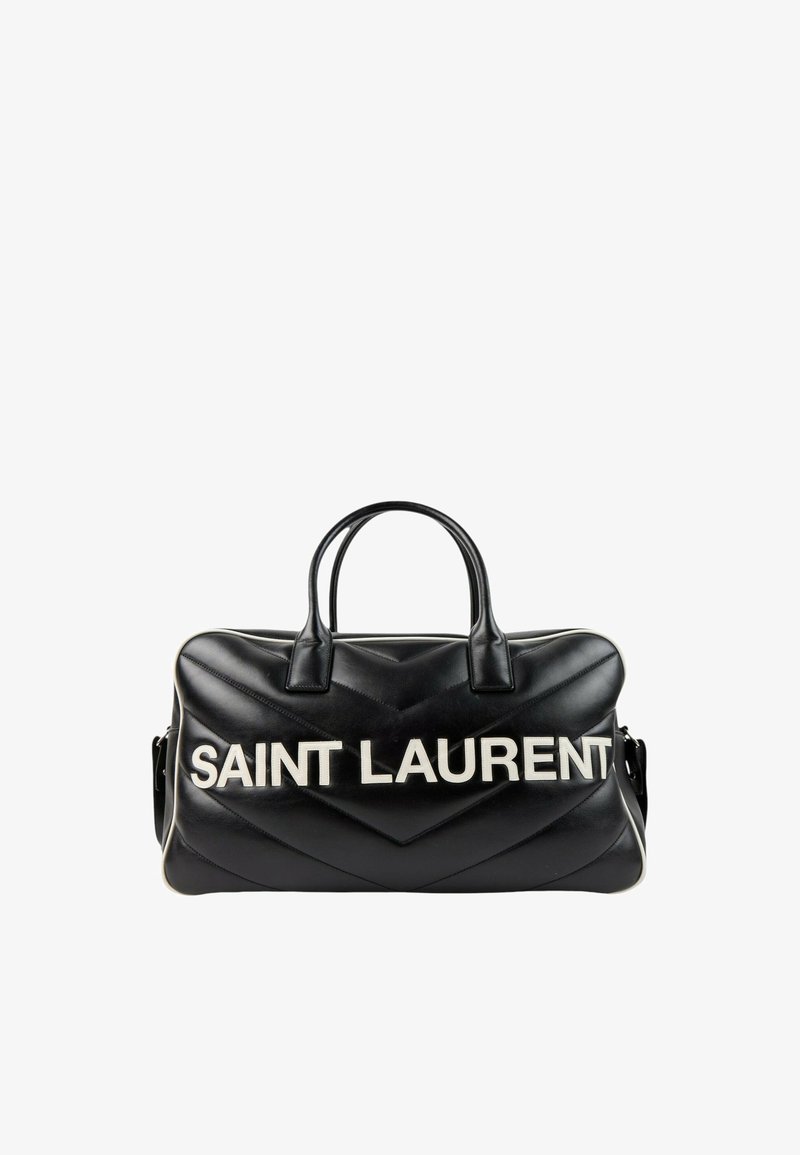 Sac à main Saint Laurent en cuir noir avec deux poignées et logo blanc en caractères gras à l'avant sur fond blanc.