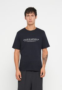 Μπλε βαμβακερό T-shirt με κοντά μανίκια, με λευκό κείμενο και λογότυπο της μάρκας. Απλός στρογγυλός γιακάς, άνετη εφαρμογή.