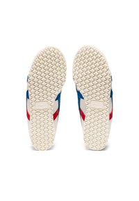 Schoenzool met een witte rubberen Zool, met een getextureerd diamantpatroon, blauwe en rode accenten op een crèmekleurige achtergrond.