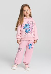 Set di felpa e pantaloni della tuta rosa con personaggi dei cartoni animati, con testo "LOVE" e accenti colorati. Materiale morbido, vestibilità rilassata, polsini a coste.