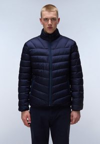 Donkerblauwe pufferjack met horizontaal gestikt patroon, hoge kraag en voorrits. Zijzakken met blauwe bies accentueren het ontwerp.