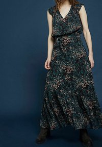 Robe maxi en tissu noir, avec un motif floral en teal et or, décolleté en V, manches courtes et un détail de taille nouée.