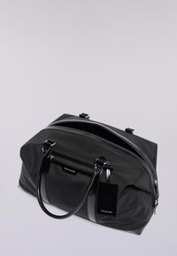 Černá nylonová sportovní taška s lesklými koženými doplňky, dvěma rukojeťmi, horním zipem a přední kapsou na zip. Obsahuje štítek s logem značky.