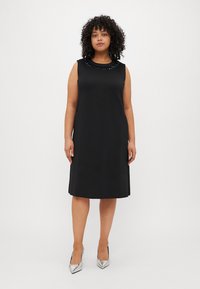 Μαύρο αμάνικο φόρεμα με στρογγυλή λαιμόκοψη και διακοσμητικές χάντρες. Λείος ύφασμα, σιλουέτα Α-γραμμής, έως το γόνατο, συνδυασμένο με ασημ�ένια τακούνια.