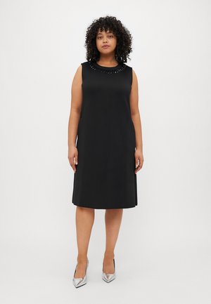 Black sleeveless dress with a round neckline featuring decorative beading. Smooth fabric, A-line shape, knee-length, paired with silver heels.