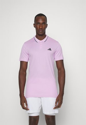 Lichtroze poloshirt met zwarte accenten, drieknoopsluiting en korte mouwen. Heeft een zwart logo op de linkerkant van de borst.