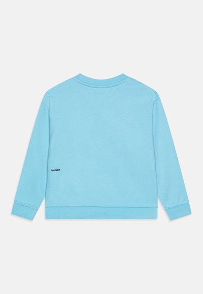 Lys blå genser med lange ermer, rund hals, ribbestrikkede mansjetter og en liten svart logo på venstre bakside.