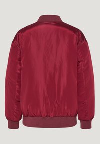 Red satin bomber jacket with a ribbed collar and cuffs, featuring long sleeves and a gathered hem for a structured fit. No pockets visible.