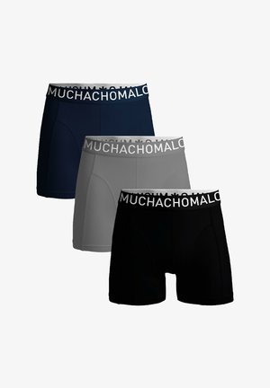 Tre paia di boxer in navy, grigio e nero, con un elastico bianco su cui è stampato "MUCHACHO". Texture liscia e design aderente.