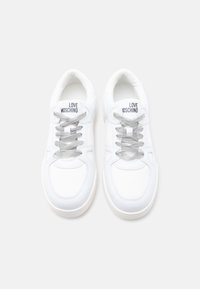 Λευκά sneakers Love Moschino με ανοιχτό γκρι κορδόνια, άνω μέρος από δίχτυ και δέρμα, με θέα από πάνω σε απλό φόντο.