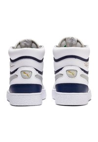 Paire de baskets montantes blanches avec des touches bleu marine et gris et un logo Puma doré, vue de dos.