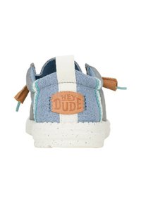Zapato de lona azul y gris tipo slip-on con una franja blanca, etiqueta de piel marrón y acentos turquesas. Presenta una suela texturada y moteada.