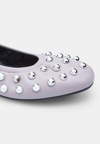 Bailarinas de suave cuero lavanda, adornadas con tachuelas metálicas plateadas, con punta redondeada y suela negra flexible.