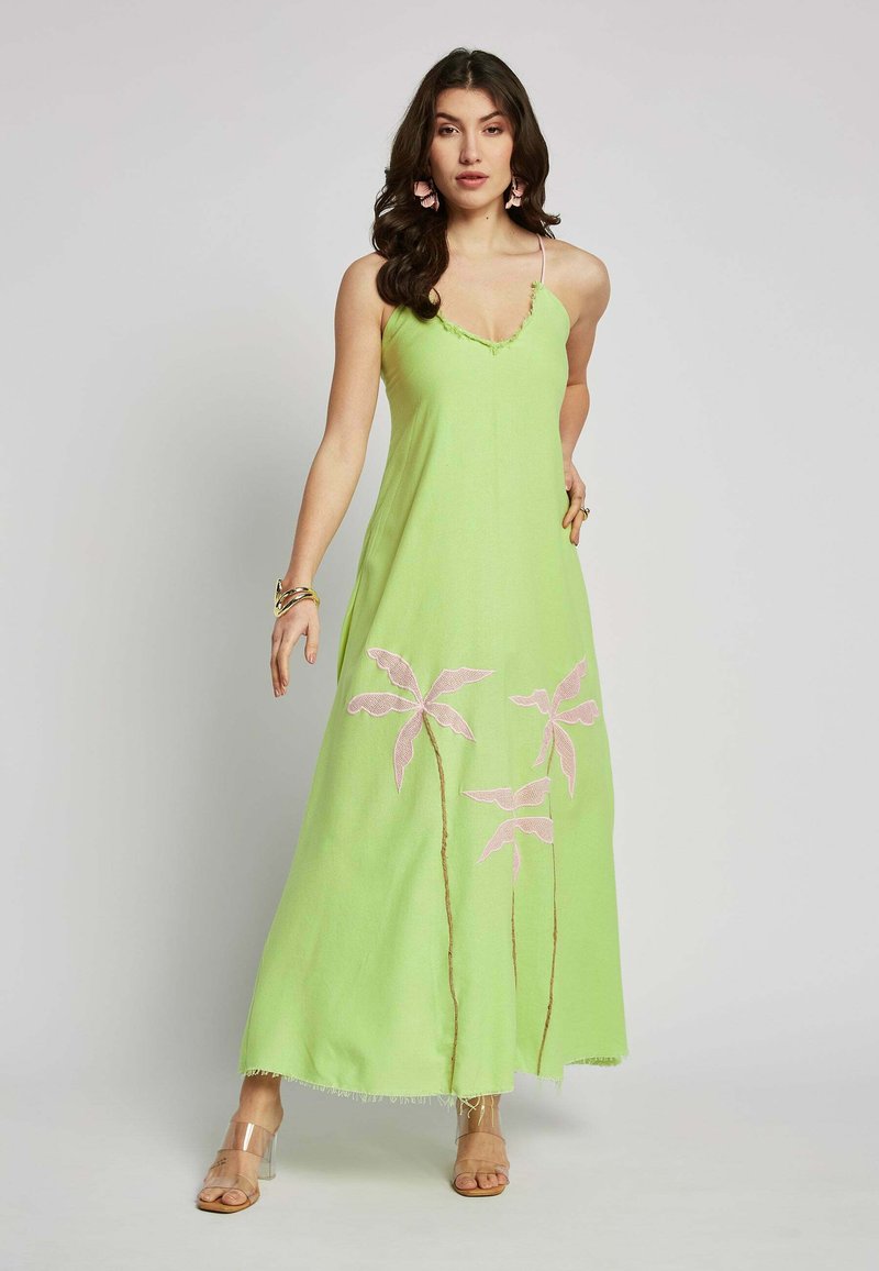 Langes, hellgrünes Maxikleid mit Spaghettiträgern, das mit rosa gestickten Palmen und Fransenakzenten am Saum versehen ist. Durchsichtige High-Heel-Sandalen.