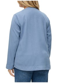 Veste bleu clair à manches longues au design simple, fabriquée en tissu lisse. Elle présente un col et des détails de couture sur l'ourlet.