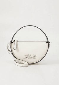 Λευκή δερμάτινη τσάντα με κυκλικό σχέδιο, μαύρο φινίρισμα και ασημί λογότυπο. Περιλαμβάνει ρυθμιζόμενο λουρί και φερμουάρ κλεισίματος.