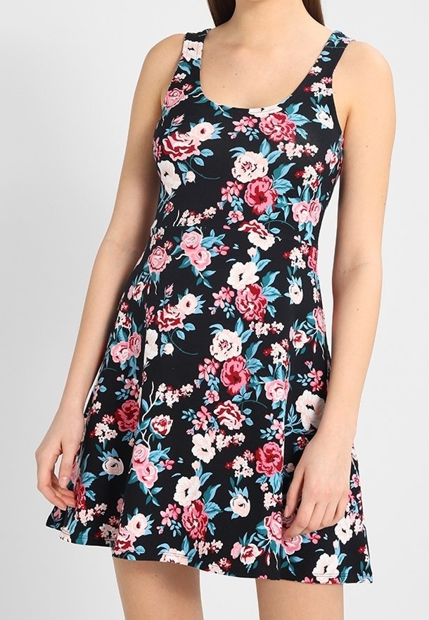 Robe noire sans manches avec motif floral rose, rouge et blanc, cintrée à la taille et évasée en une jupe courte.
