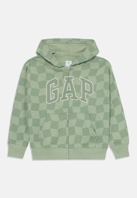 Felpa con zip verde chiaro realizzata in tessuto morbido, caratterizzata da un motivo geometrico e il logo 'GAP' in beige chiaro. Include tasche anteriori e un cappuccio.