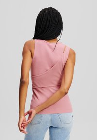 Lichtroze geribde tanktop met asymmetrisch ontwerp, met een diagonale naad en dunne bandjes. Gekocht bij blauwe denim spijkerbroek.