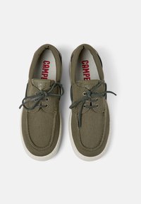 Grüne Stoffschuhe mit strukturiertem Obermaterial, runder Zehenpartie und kontrastierender weißer Gummisohle. Mit Schnürsenkeln und Camper-Branding im Inneren.