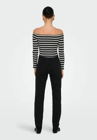 Sorte høj talje jeans parret med en sort-hvid stribet off-the-shoulder top. Toppen har ribbet tekstur og lange ærmer.