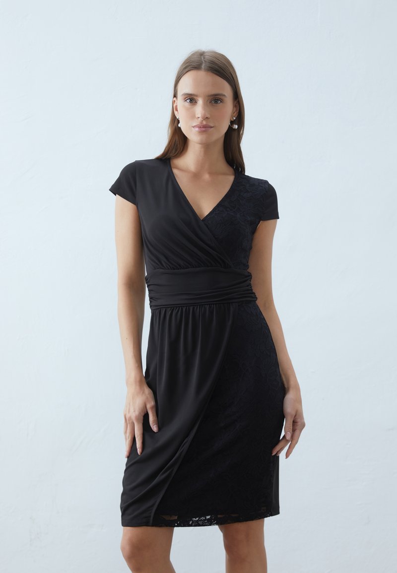 Black wrap dress featuring a V-neck, short cap sleeves, and a textured lace panel on one side; smooth fabric with a gathered waist detail.