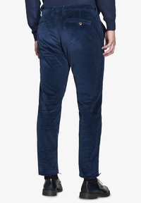 Pantaloni in corduroy blu navy con finitura texturizzata, dotati di due tasche posteriori, passanti per cintura e un design a gamba affusolata.