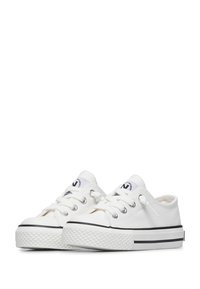 Białe trampki płócienne z teksturowaną gumową podeszwą, czarnym akcentem wzdłuż, sześcioma otworami na sznurowadła oraz naszywką z logo na języku.