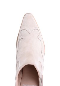 Suede slip-on sko i lys beige med spiss tå, dekorative bølgekantede kanter og en jevn indersåle.