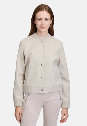 Veste courte gris clair avec un col rond, des boutons-pression et des poignets côtelés. Fabriquée en tissu doux avec des poches latérales.