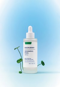 Szklana butelka z kroplomierzem z białą nakrętką i przezroczystym korpusem. Etykieta zawiera niebieski i zielony tekst. Zawiera 50 ml. Umieszczona na niebieskim tle z liściem.