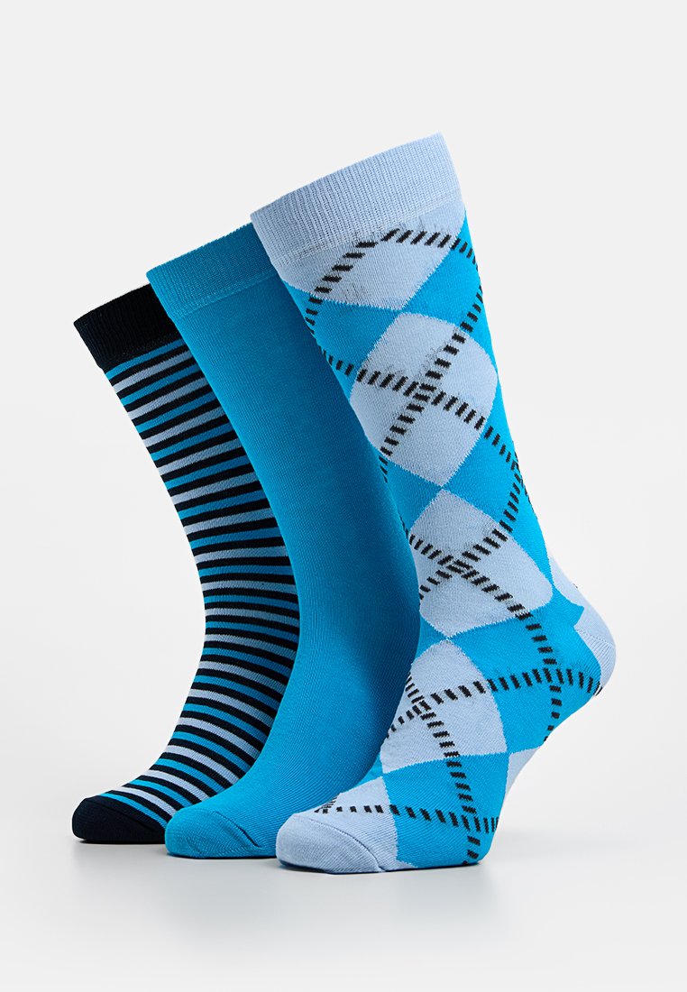 Drie paar sokken in verschillende tinten blauw: één geheel donkerblauw met strepen, één geheel lichtblauw en één met een ruitpatroon in lichtblauw met zwarte accenten.