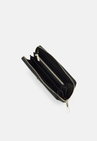 Svart läderplånbok med guldaccessoarer, som har flera fack och ett dragkedjestängning. Slät yta och rektangulär form.