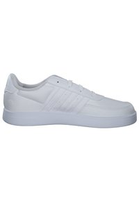 Baskets blanches avec un dessus en synthétique lisse, design à lacets, accents perforés et semelle en caoutchouc. Style minimaliste avec trois rayures sur les côtés.
