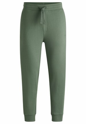 Joggers en coton vert avec taille élastique à cordon de serrage, poignets côtelés et branding discret. Texture lisse et coupe fuselée pour le confort.